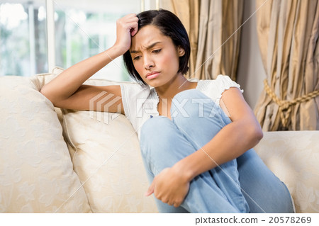 Frowning brunette sitting on the sofa Frowning brunette sitting on the sofa 20578269