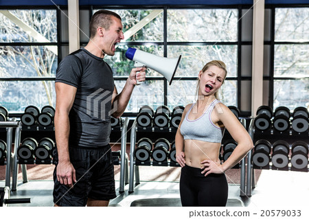 Male trainer motivating fit woman with megaphone 20579033
