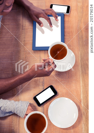 Colleagues holding coffee cups while using technologies 20579034