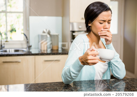 Frowning woman with toothache holding cup 20579208