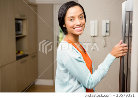 Smiling brunette with hand on refrigerator Smiling brunette with hand on refrigerator 20579351