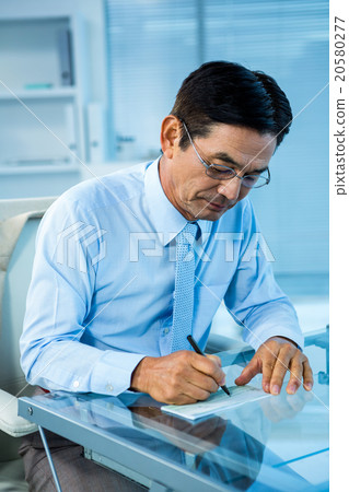 Businessman on his desk signing document 20580277