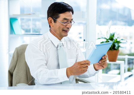 Smiling asian businessman using tablet 20580411