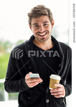 Handsome man using smartphone holding disposable cup 20580436