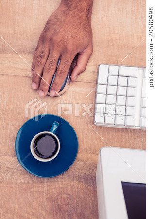 Businessman using mouse by coffee cup while working 20580498