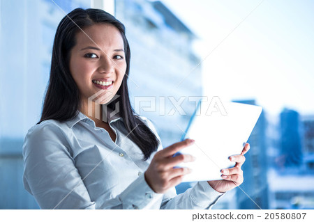 Smiling businesswoman holding tablet and looking at camera Smiling businesswoman holding tablet and looking at camera 20580807