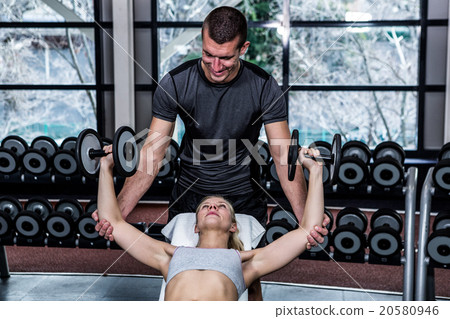 Fit woman doing dumbbells exercise with trainer 20580946