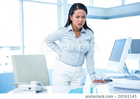 Frowning businesswoman with back ache Frowning businesswoman with back ache 20581145