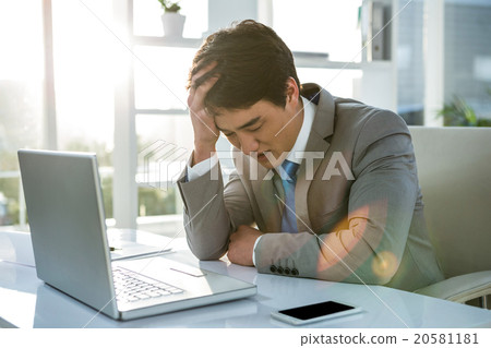 Tired businessman holding his head 20581181