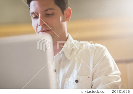 Smiling male student using laptop 20581636