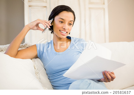 Smiling brunette on phone call holding sheets 20581637