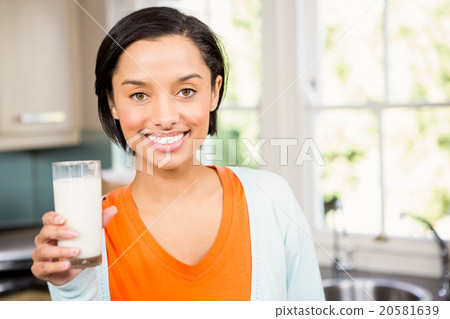 Happy brunette holding glass of milk 20581639