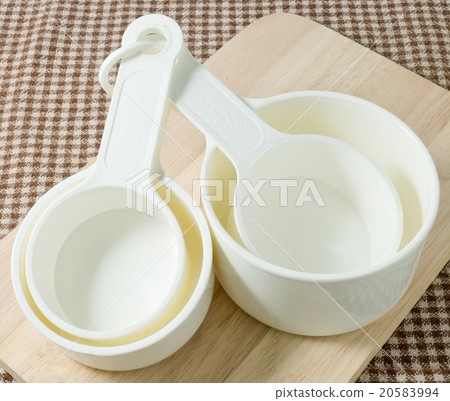 White Plastic Measuring Cups on Wooden Board White Plastic Measuring Cups on Wooden Board 20583994