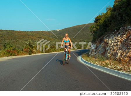 Woman cyclist riding a bike on a mountain road Woman cyclist riding a bike on a mountain road 20588550