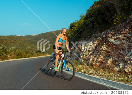 Woman cyclist riding a bike on a mountain road Woman cyclist riding a bike on a mountain road 20588551