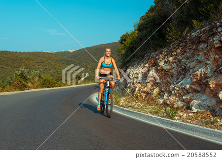 Woman cyclist riding a bike on a mountain road 20588552