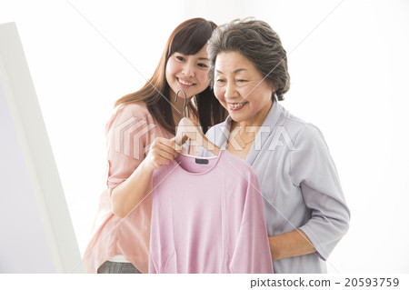 選擇衣服的高級婦女和年輕婦女 選擇衣服的高級婦女和年輕婦女 20593759