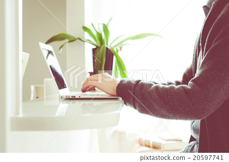 在家裡的桌子上操作筆記本電腦的人 20597741