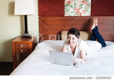 Japanese lady lying on the bed and using a laptop Japanese lady lying on the bed and using a laptop 20599363