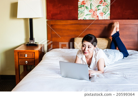 Japanese lady lying on the bed and using a laptop Japanese lady lying on the bed and using a laptop 20599364