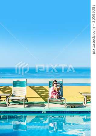 Asian lady who is relaxing at the resort hotel's poolside 20599385