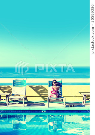 Asian lady who is relaxing at the resort hotel's poolside 20599386