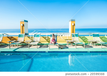 Asian lady who is relaxing at the resort hotel's poolside 20599388