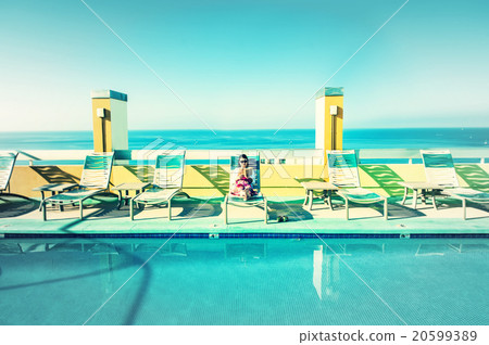 Asian lady who is relaxing at the resort hotel's poolside 20599389