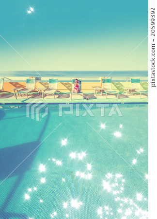 Asian lady who is relaxing at the resort hotel's poolside 20599392