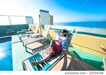 Asian lady who is relaxing at the resort hotel's poolside 20599396