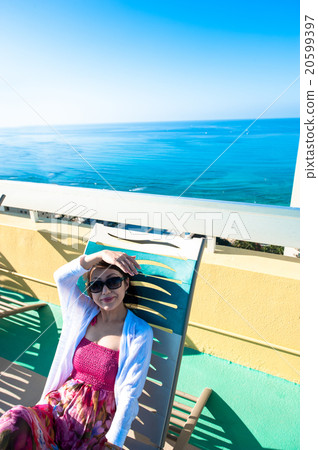 Asian lady who is relaxing at the resort hotel's poolside 20599397