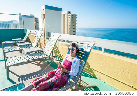 Asian woman reading at the resort hotel's poolside 20599399