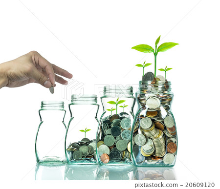 Hand putting mix coins and seed in clear bottle on white backgro Hand putting mix coins and seed in clear bottle on white backgro 20609120