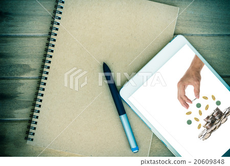 Notebook with tablet show the Hand holding and adding a coin on Notebook with tablet show the Hand holding and adding a coin on 20609848
