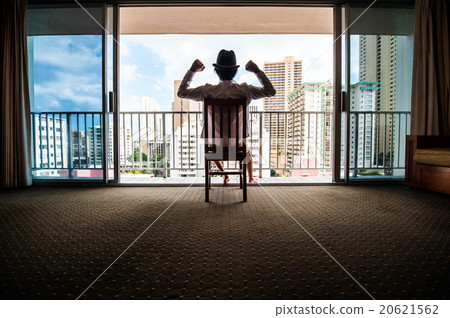 A man sitting in a chair and looking out the window from the window 20621562