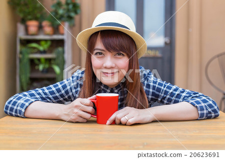 wear hat woman sitting in outdoor with warm drink wear hat woman sitting in outdoor with warm drink 20623691