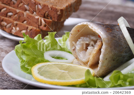 pickled herring roll with onion on lettuce, lemon  20642369
