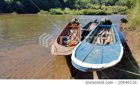Three boats were tied up in the river with blue  20646116