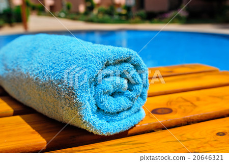blue rolled-up towel lying on a lounger near pool blue rolled-up towel lying on a lounger near pool 20646321