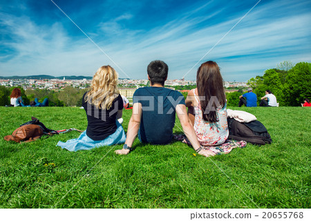 Three tourists friend sitting on the green grass  20655768