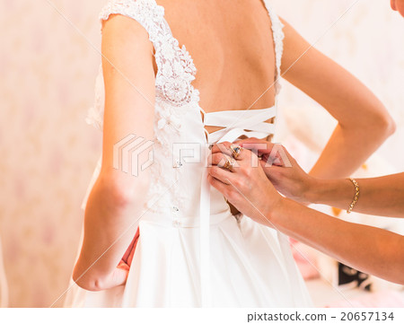 bridesmaid tying bow on wedding dress bridesmaid tying bow on wedding dress 20657134