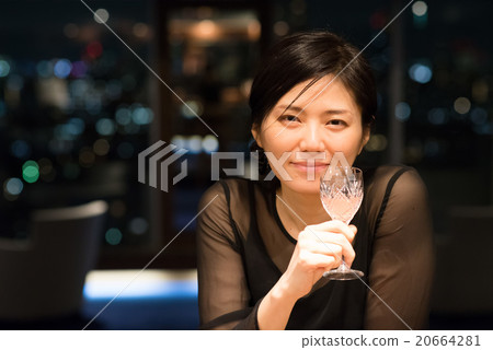 A woman drinking at a bar with a night view A woman drinking at a bar with a night view 20664281