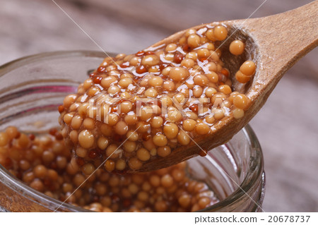 Dijon mustard on a wooden spoon in a glass jar Dijon mustard on a wooden spoon in a glass jar 20678737