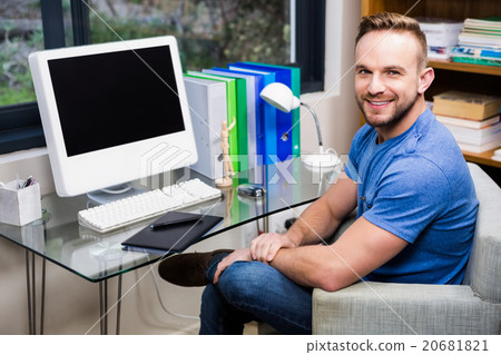 Smiling designer posing while sitting at desk Smiling designer posing while sitting at desk 20681821