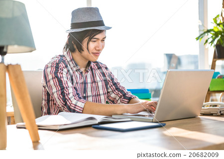 Smiling hipster businessman using laptop 20682009