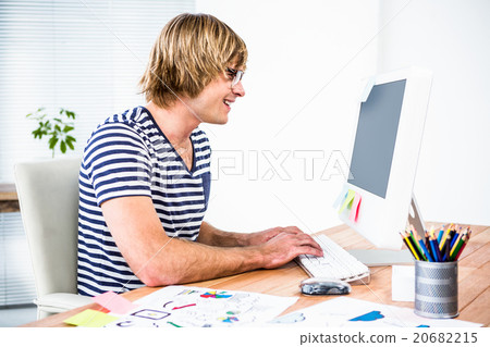 Smiling hipster businessman using his computer Smiling hipster businessman using his computer 20682215
