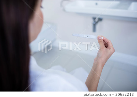 Over shoulder view of woman looking at her pregnancy test 20682218