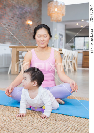Calm mother meditating on mat at home 20682264