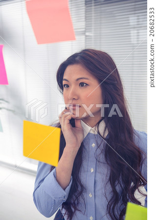 Asian businesswoman using sticky notes on wall Asian businesswoman using sticky notes on wall 20682533