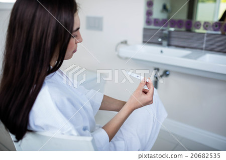 Unhappy woman sitting while looking at pregnancy test 20682535